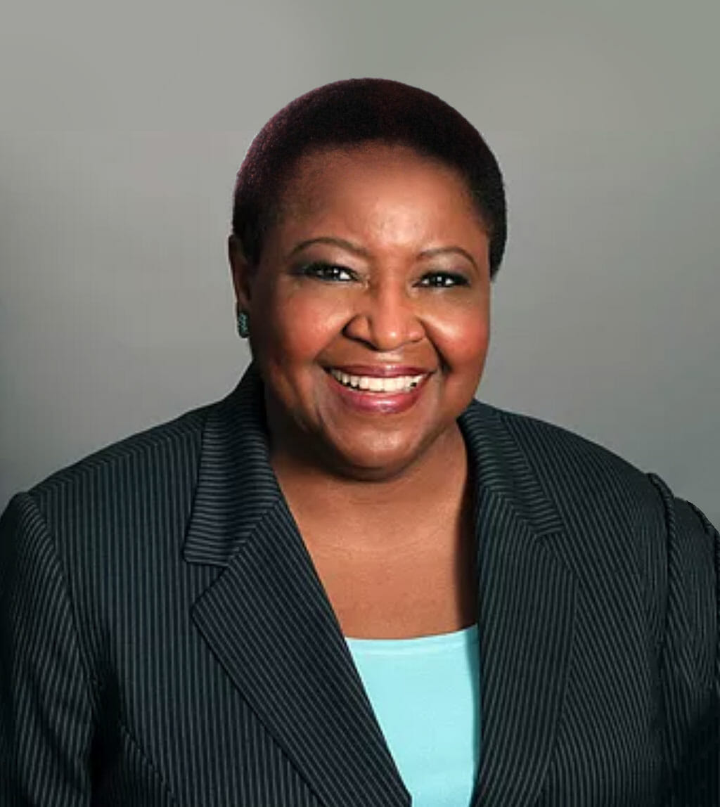 black woman smiling with shirt back hair wearing a black blazer and light blue shirt