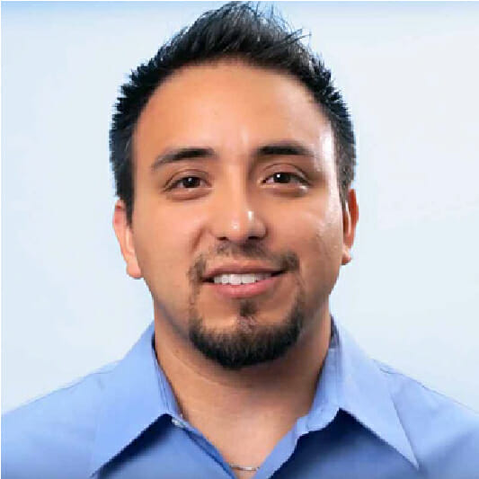 hispanic man smiling with a dark goatee and short brown hair wearing a blue button down shirt
