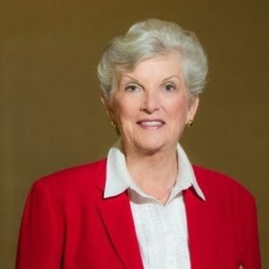 white woman with a white collared shirt and red blazer