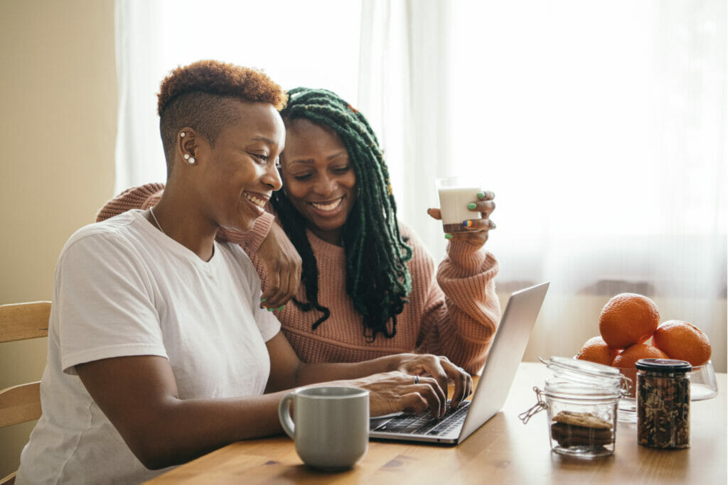 smiling couple having coffee and looking at a laptop screen