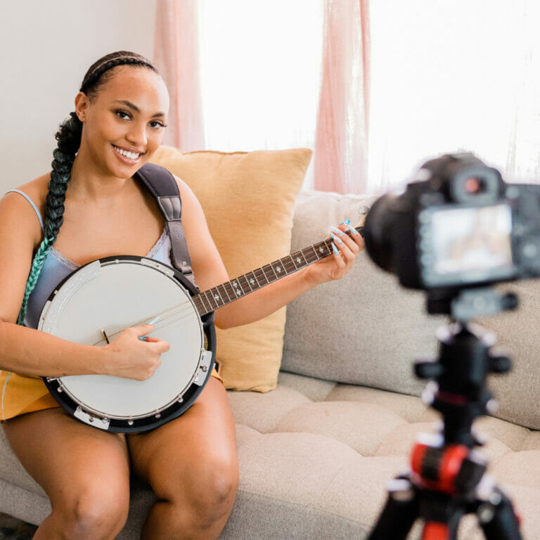 young woman filming a video of herself playing a banjo