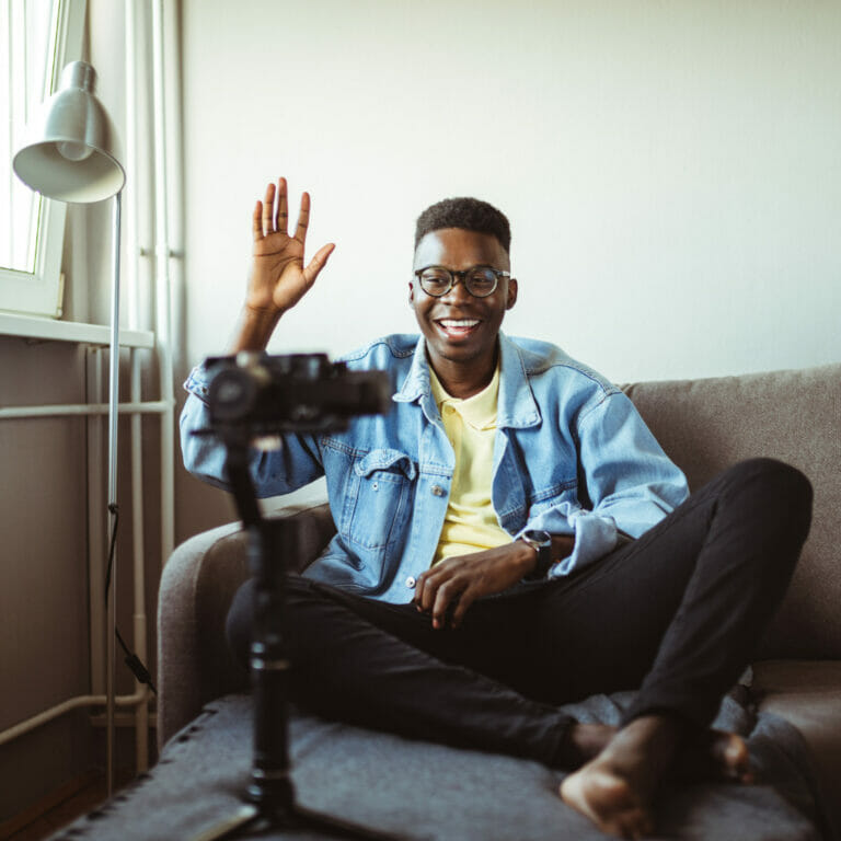 young man filming a video of himself while sitting on a couch