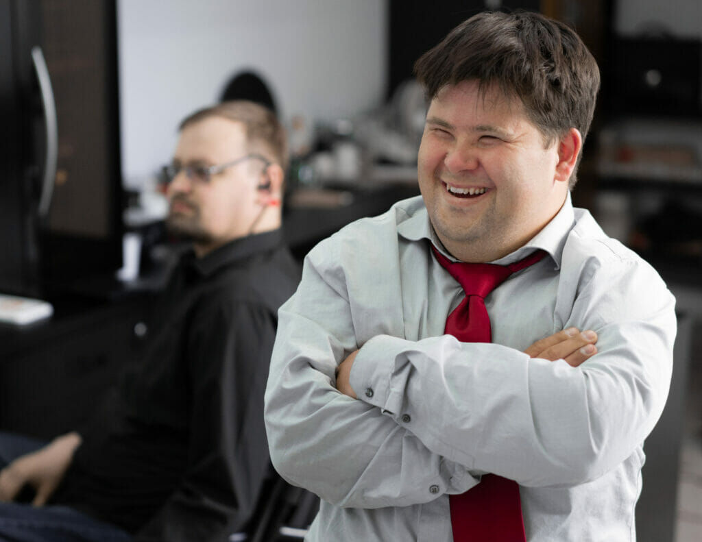 Man with Down Syndrome in a suit smiling during a meeting.