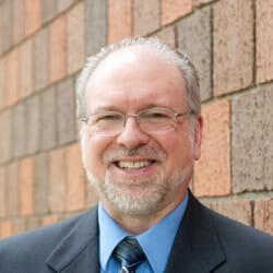 Don smiling in front of a brick wall