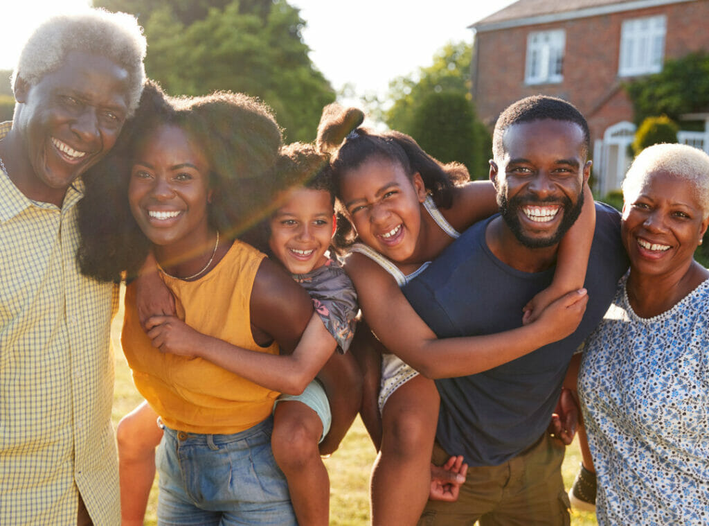 Multigenerational black family smiling in front of a home