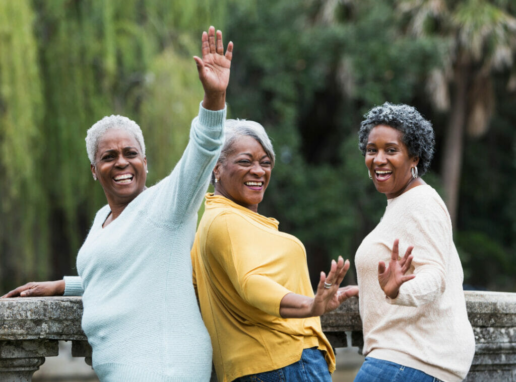 Three older black women smile and pose for a picture