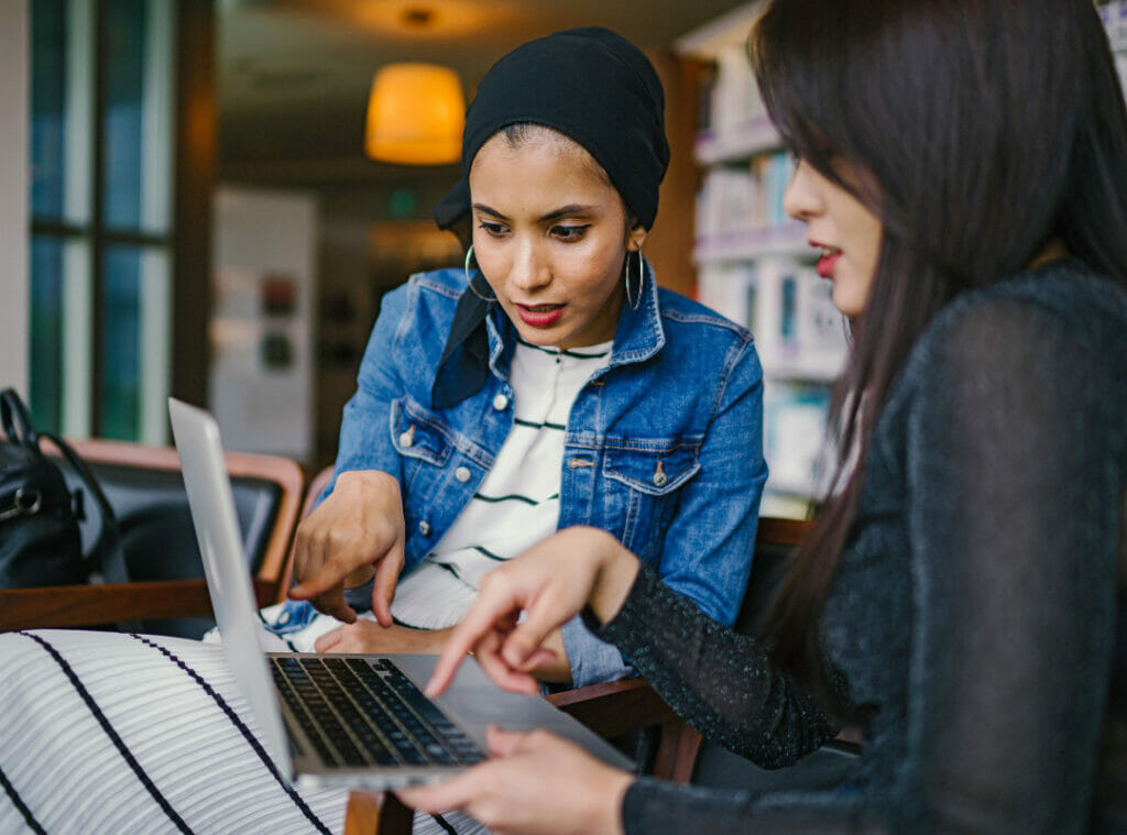 Two women having a conversation while looking at a laptop