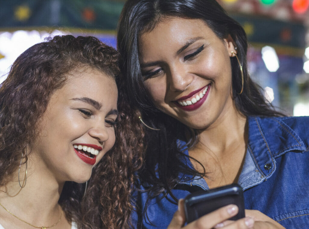 Two women smiling at a message on a cell phone