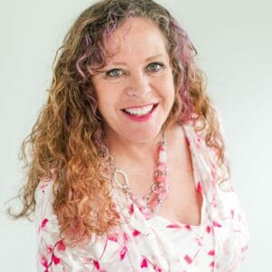 Headshot of Andi smiling in front of a cream background