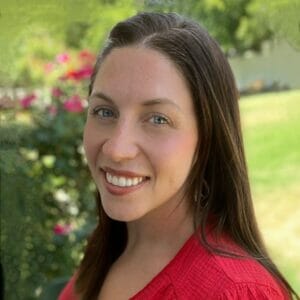 Headshot of Amy Smith in a red blouse with a garden backdrop