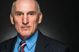 Headshot of Glen Cone in a suite and black backdrop