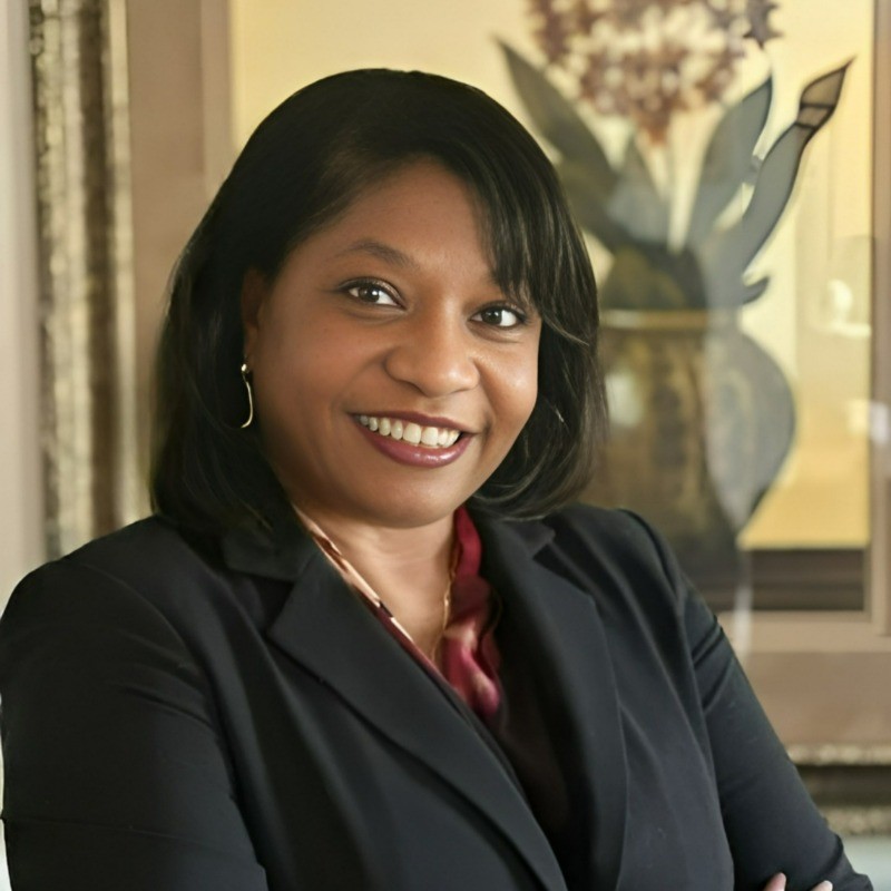 headshot of a smiling black woman with shoulder length black hair wearing a black blazer