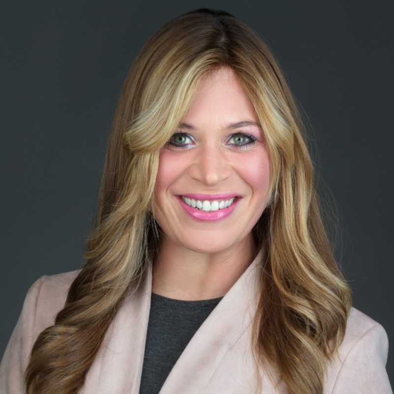 headshot of a smiling white woman with long blonde hair in a beige blazer and dark blue shirt