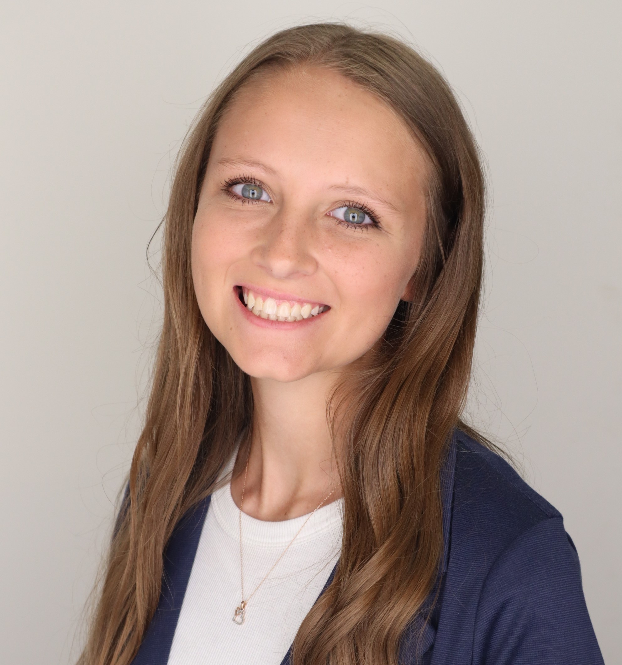 white woman with long blonde hair smiling and wearing a blue blazer and white t-shirt