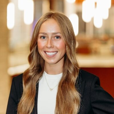 white woman with long strawberry blonde hair wearing a black blazer and white shirt