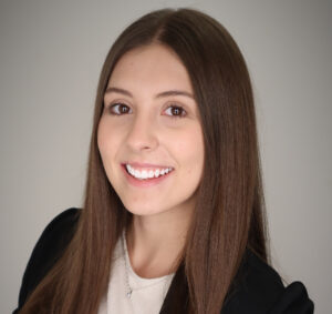 white woman smiling with long brown hair wearing a black blazer and white t-shirt