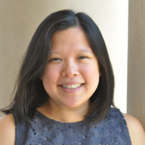 headshot of a smiling asian woman with long brown hair wearing a sleeveless blue shirt
