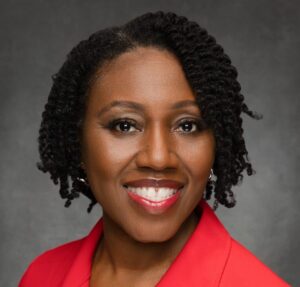 headshot of a black woman smiling wearing a red suit