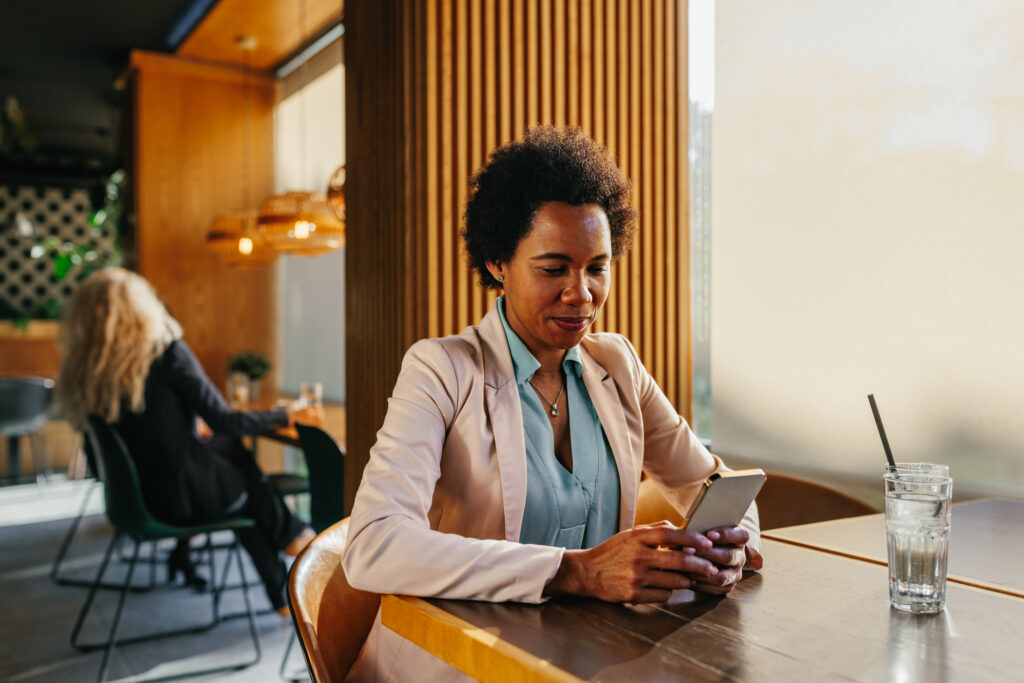 Businesswoman using phone while waiting for coffee In Coffee Shop