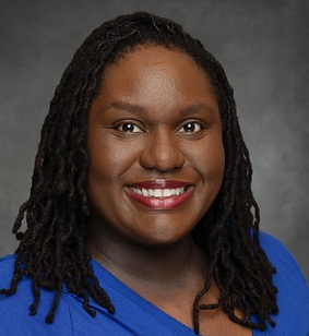 headshot of black woman with long brown hair smiling in a blue shirt
