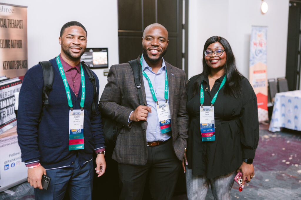 two men and one woman of color smiling at Symposium