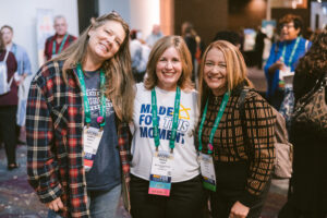 Three women smiling while attending Symposium