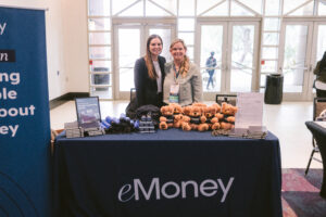 Two women smiling while exhibiting at Symposium
