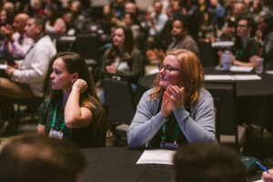 audience attending the and applauding for keynote presentation at Symposium