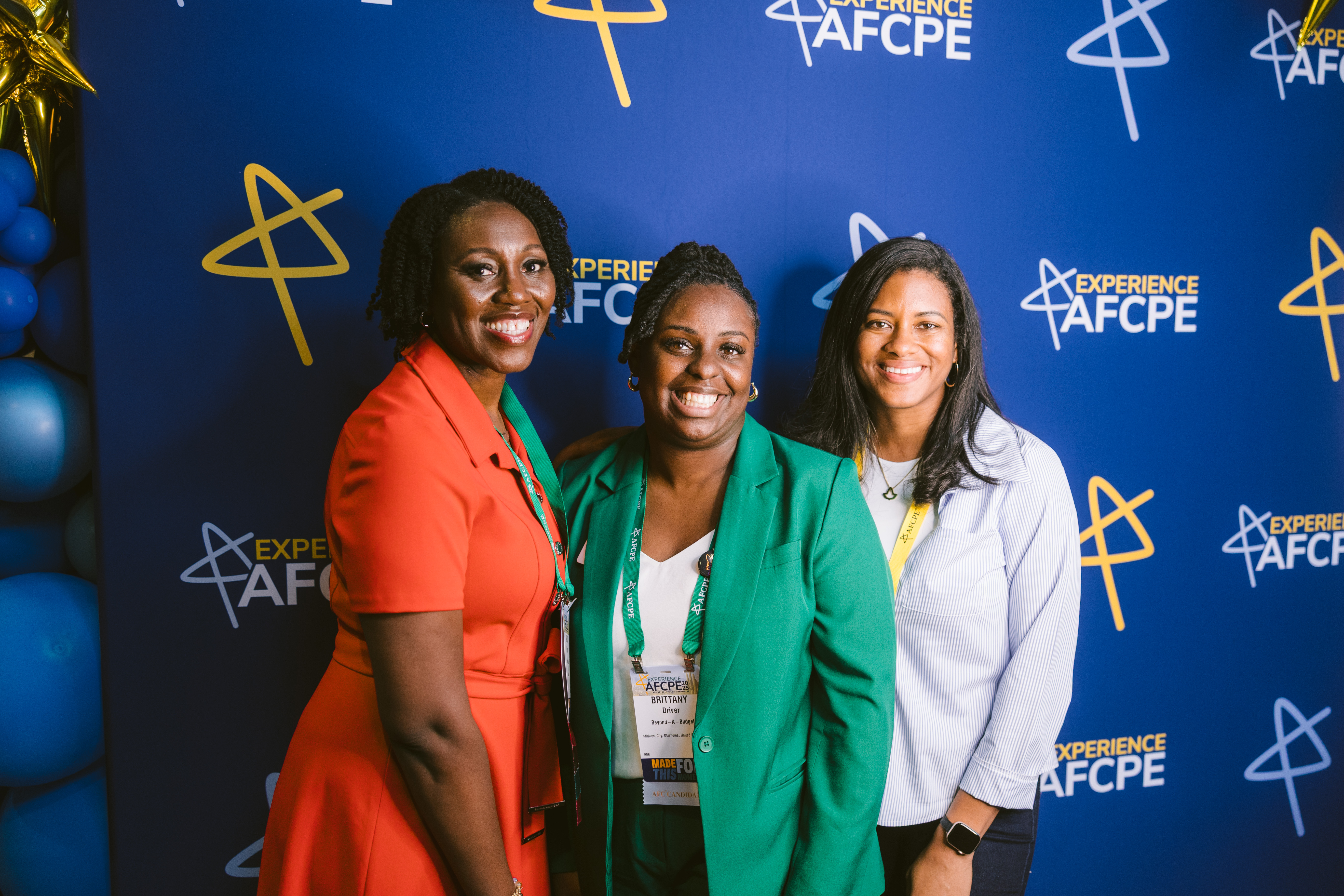 Three women standing in front of the blue Symposium branding
