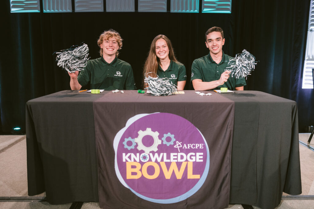 Students competing in Knowledge Bowl waving pom poms