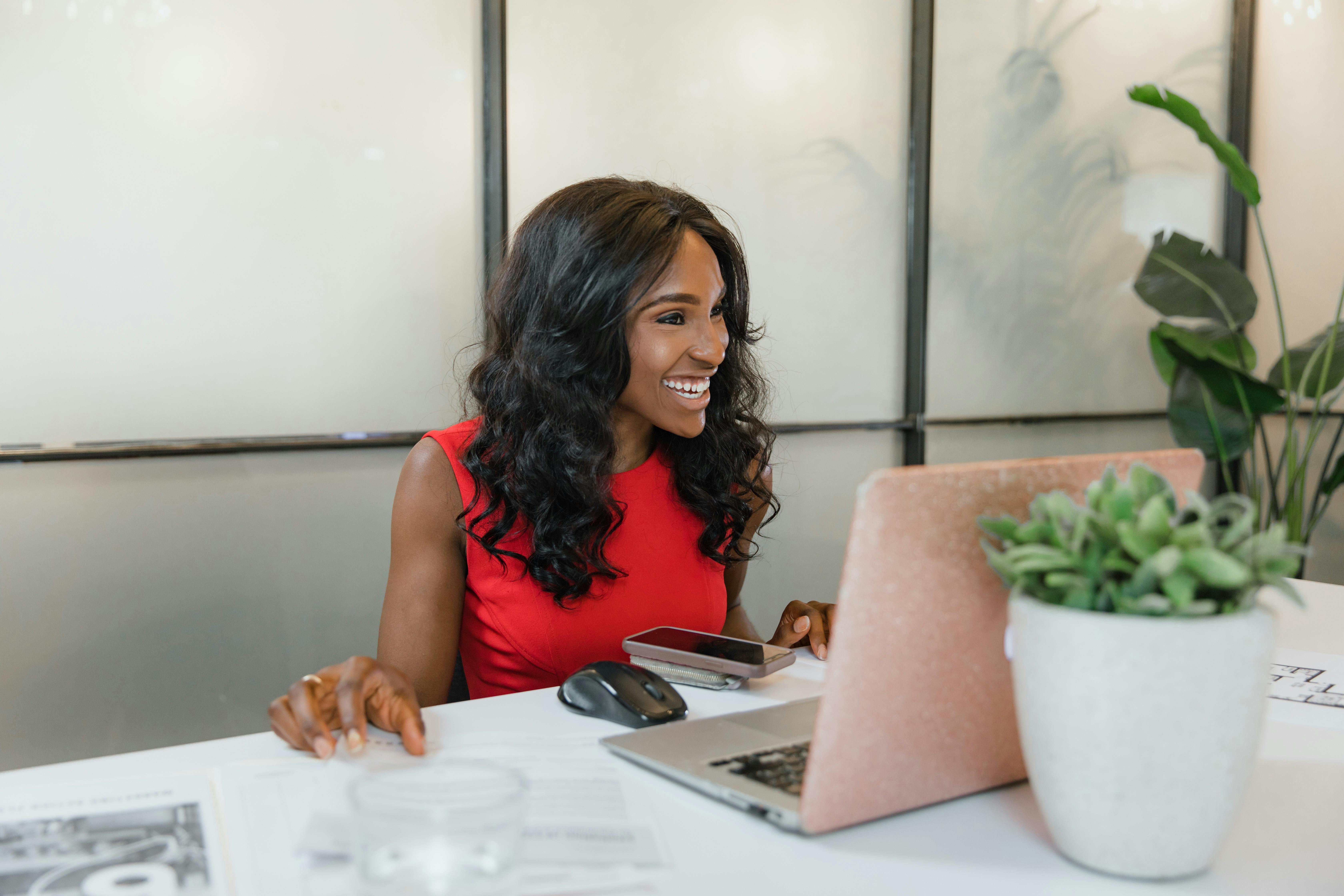 woman of color smiling while working on her laptop