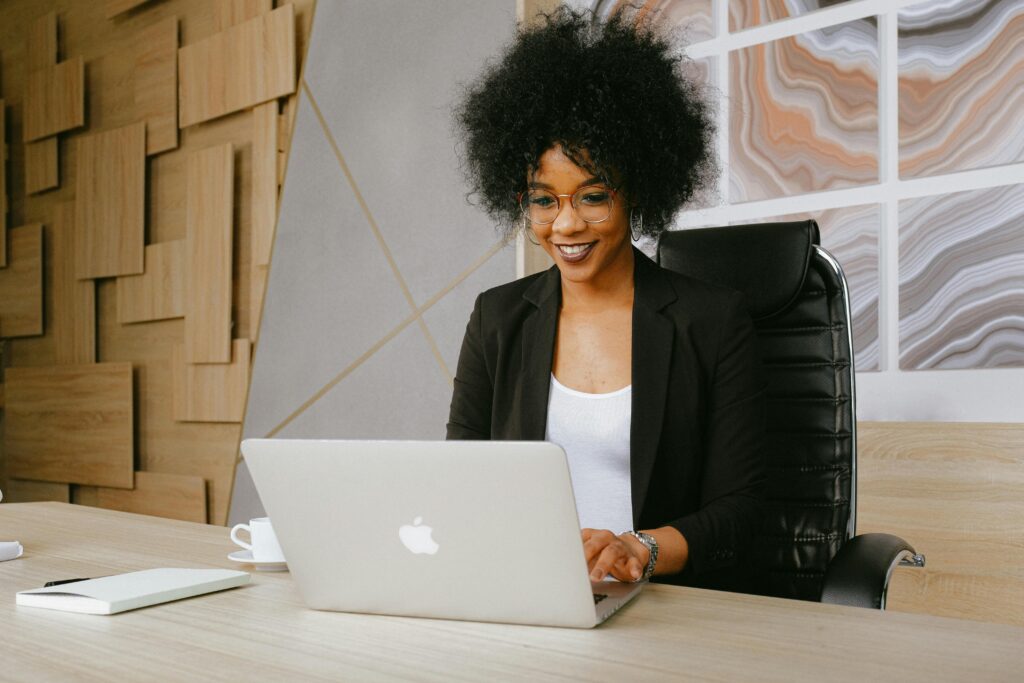 woman of color smiling while attending webinar on her laptop