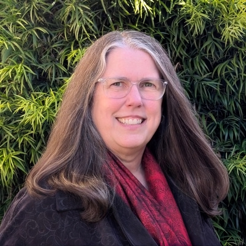 headshot of a woman with greenery in the background