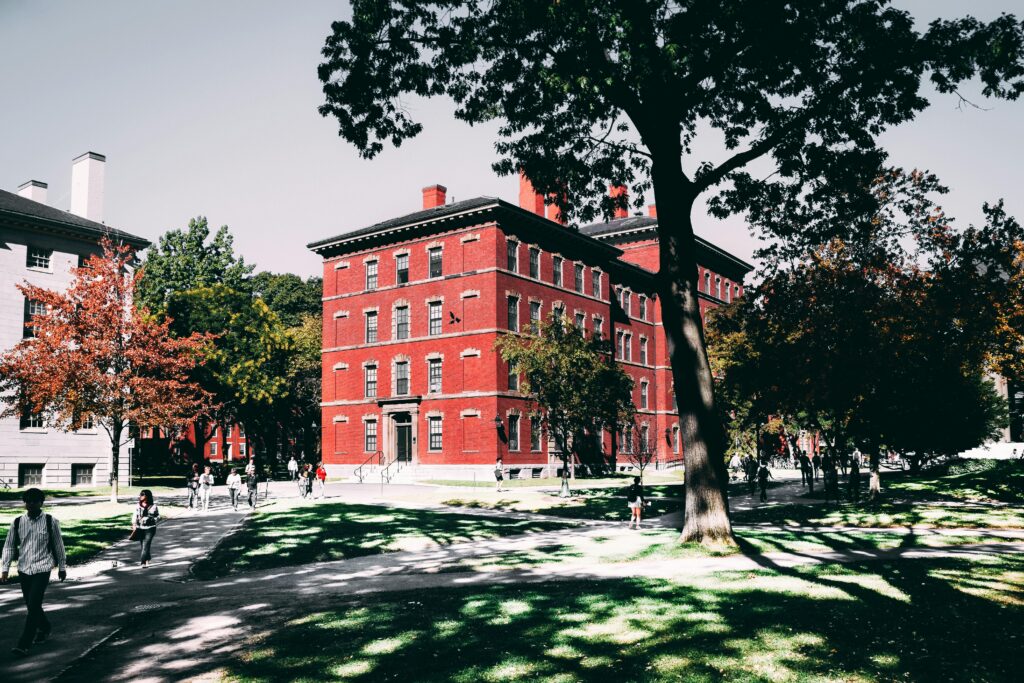 red campus building in the distance amid greenery and students walking around