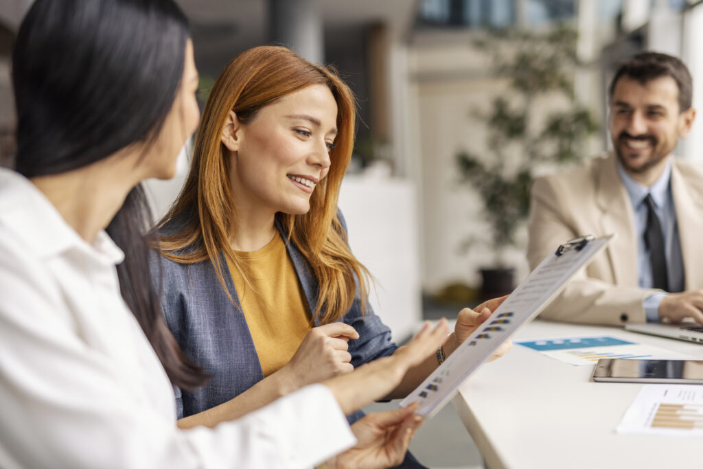 Businesswomen sitting at boardroom with team and doing case study while looking a graphs and charts.
