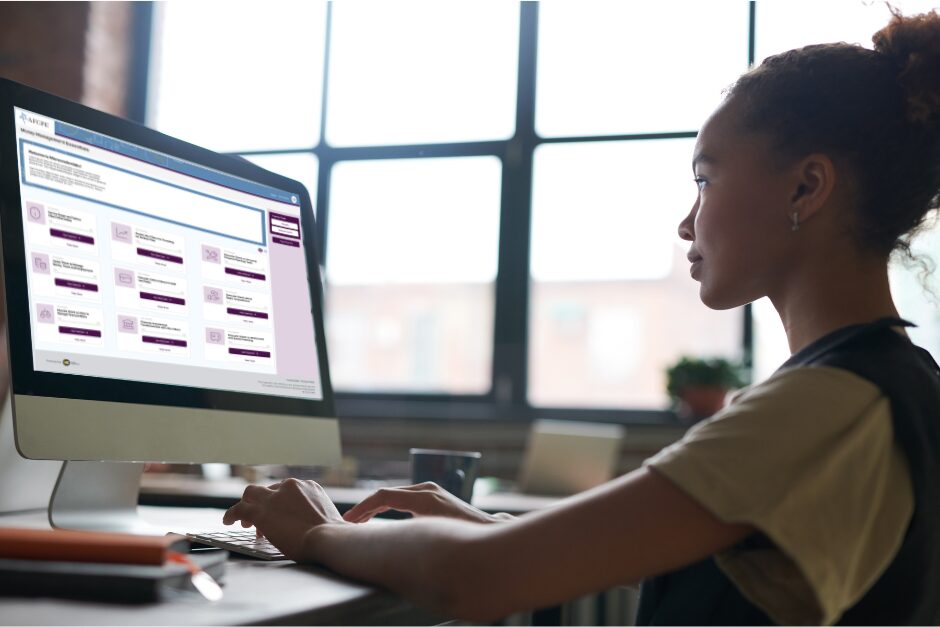 black woman sitting at her desk on the right with Money Management Essentials on her computer screen on the left