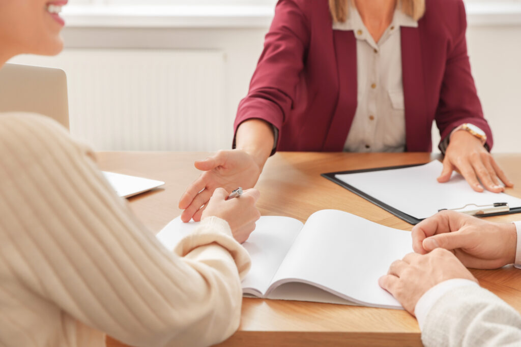 financial counselor and couple signing contract at table in new apartment, closeup