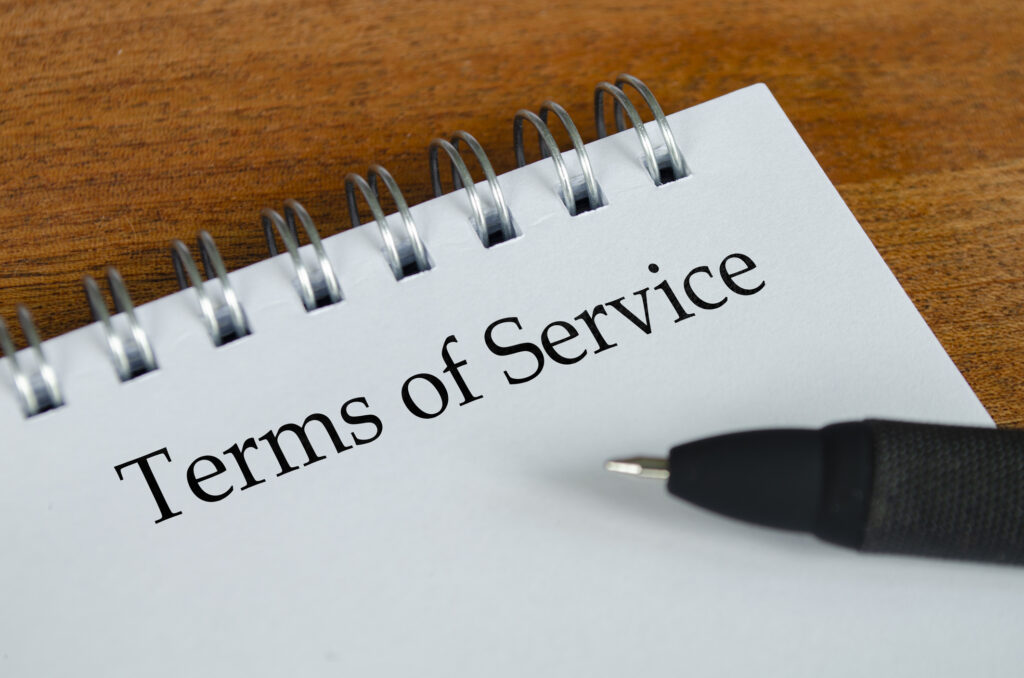 Terms of Service text on white notepad with wooden table background. Terms of Service concept