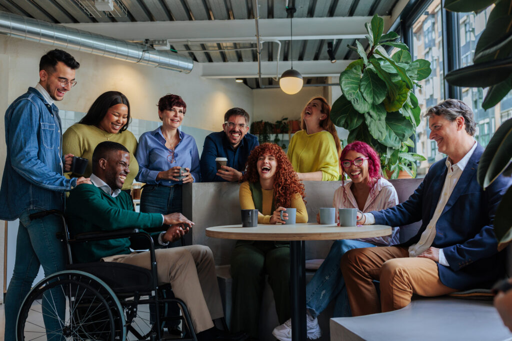 Diverse business team enjoying coffee break, laughing together in modern office