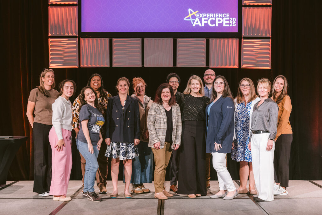 Diverse group of people on stage for a team photo at AFCPE Symposium