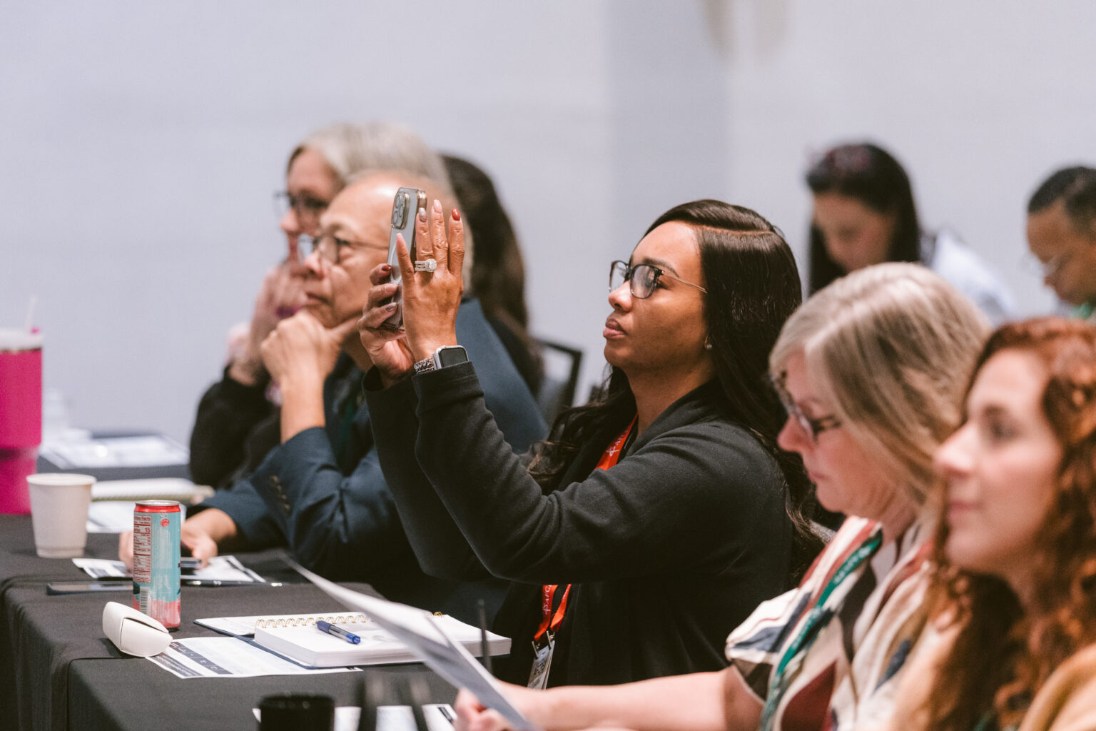 Black woman taking a picture with her cell phone during a learning session