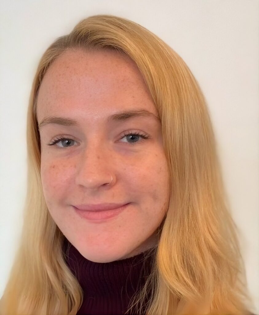 headshot of a white woman with a coy smile with long blonde hair