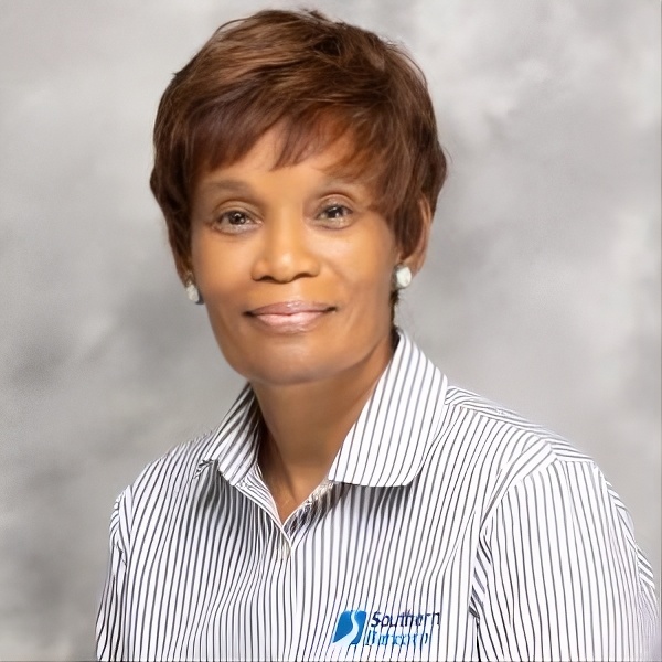 headshot of black woman with short brown hair smiling amid a gray backdrop