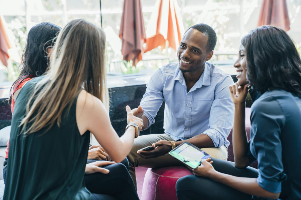 Business meeting in lobby of colorful modern office space. A black man shakes hands with a white woman smiling