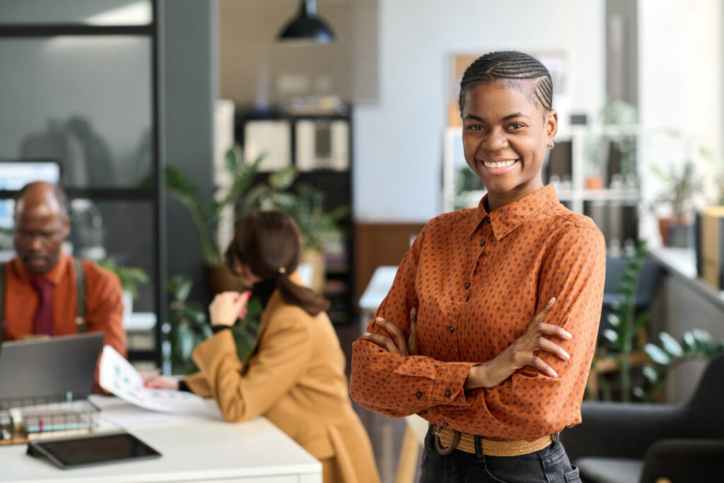 Smiling Young Woman Posing in Office with Arms Crossed