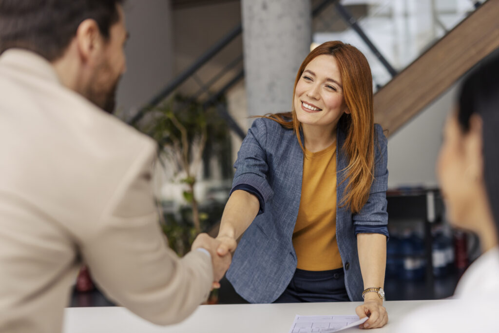 Portrait of friendly smiling female boss shaking hands with businessman on a briefing at corporate office.