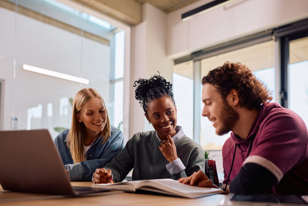 Happy diverse university students cooperating while learning in the classroom.