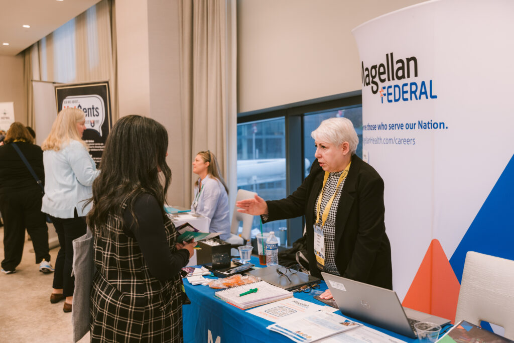 two women conversing by the exhibit booth at Symposium
