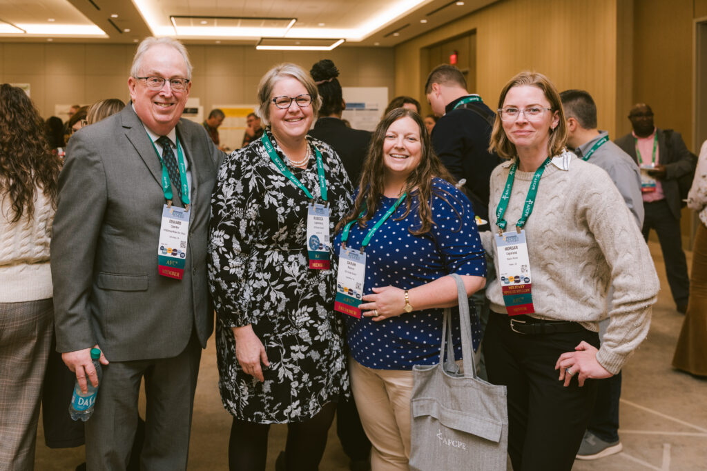 white man and three white women smiling in the hallway during a break at Symposium