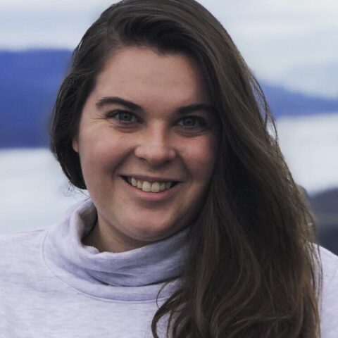 white woman with long brown hair wearing a bulky grey turtleneck
